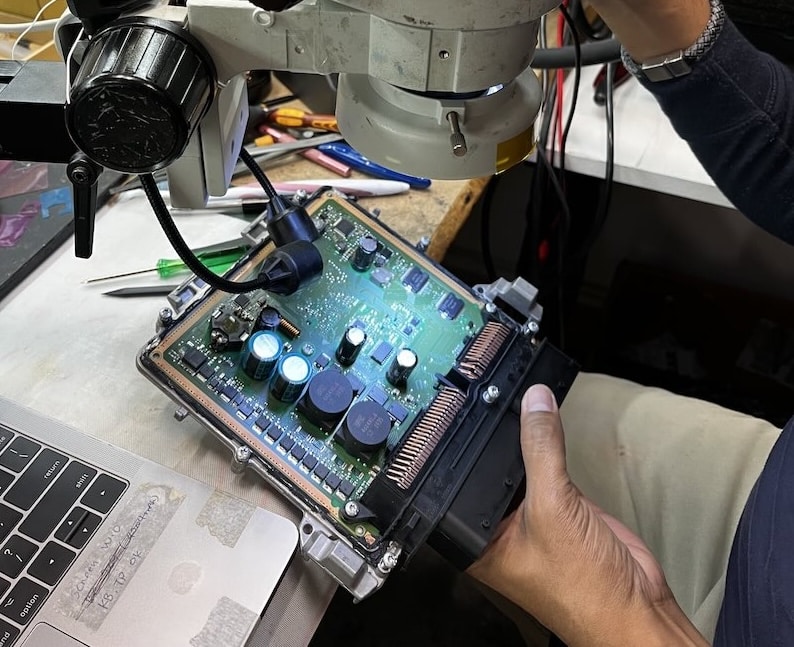 Automotive ECU circuit board being inspected under a microscope